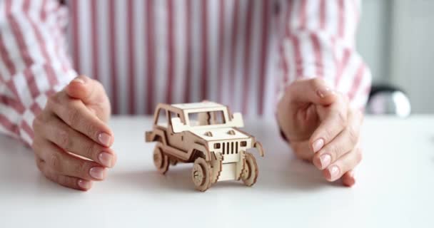 Verzekeringsagent handen knuffelen houten speelgoed auto closeup 4k film slow motion — Stockvideo