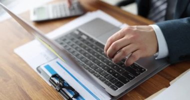 Dizüstü bilgisayarda yazan ve hesap makinesine güvenen iş adamı. 4k 'lık yakın çekim filmi yavaş çekim.