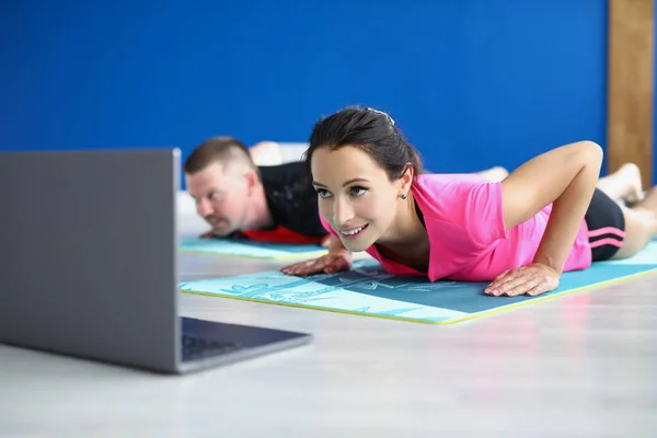 Жінка і чоловік, що практикує йогу в студії, виконують асан на килимку — стокове фото