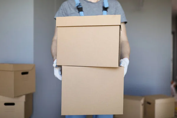 Помощник перевозит тяжелые картонные коробки с вещами владельцев в новый дом — стоковое фото