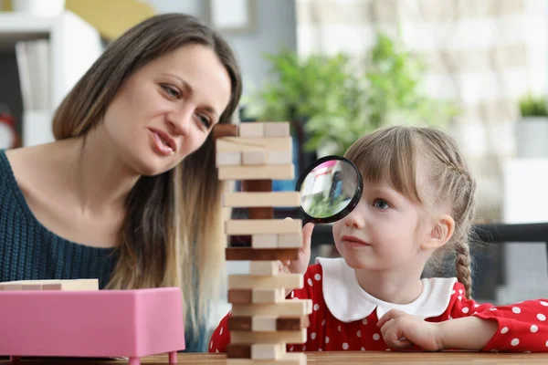 Cute little girl watch through magnifying glass on high wooden tower — Stockfoto