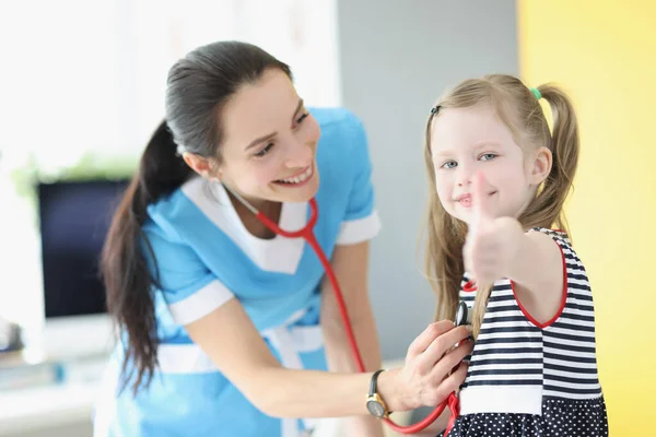 Meisje wordt onderzocht door kinderarts arts, gelukkig kind show duimen omhoog gebaar — Stockfoto