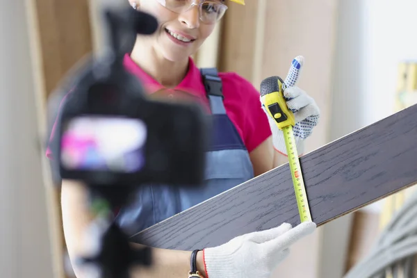 笑顔の女性建設現場作業員は、テープ測定ツールで板を測定します — ストック写真