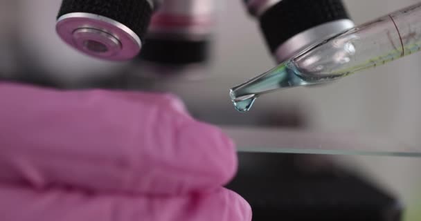 Cientista que trabalha em laboratório de biotecnologia aplica gotas de líquido na corrediça. — Vídeo de Stock