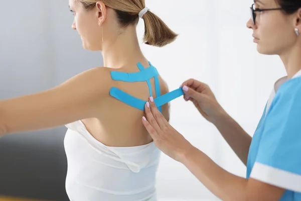 Doctor apply kinesiology tape on patient back in clinic — Stock Photo, Image