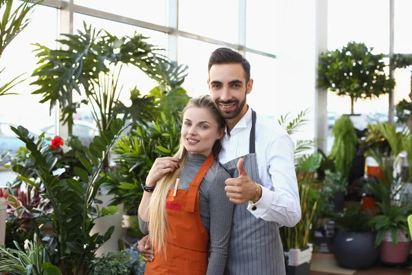 Young male and female consultants work in flower delivery shop and sale indoor plants — Stock Photo, Image