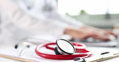 Kırmızı steteskop bilgisayarla çalışan arka plan doktorundaki tıbbi belgelerde.