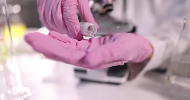 Científico químico en guantes de protección verter metal líquido en la mano en primer plano de laboratorio película 4k cámara lenta — Vídeo de stock