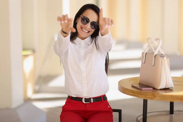 Veselá šťastná mladá žena ve stylovém oblečení ukázat nějaké symboly s rukama — Stock fotografie