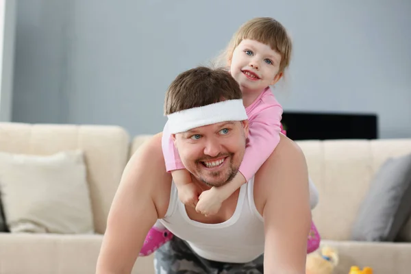 Far och dotter tillbringar tid hemma, sportaktivitet med barn på rygg — Stockfoto