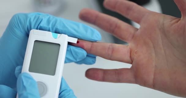 Врач в резиновых перчатках измеряет уровень глюкозы в крови пациента с помощью глюкометра крупным планом 4k фильм замедленной съемки — стоковое видео