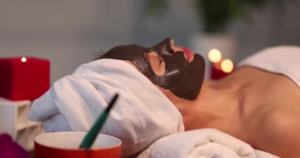 Frau mit schwarzer Lehmmaske im Gesicht liegt in Wellness-4k-Film — Stockvideo