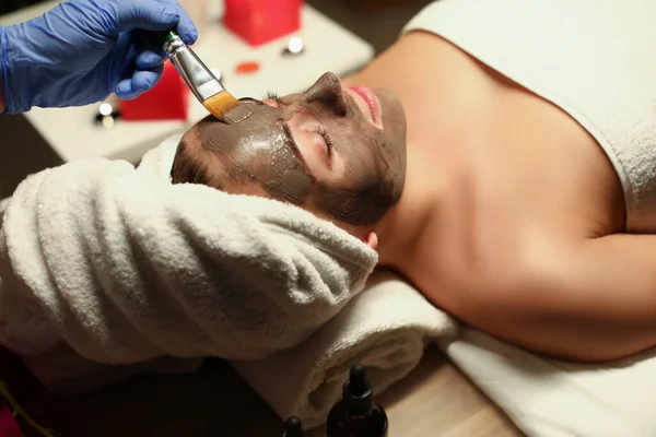 Travailleur du centre de spa appliquant un masque en argile sur le visage des clients avec un outil spécial — Photo