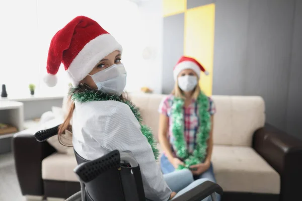 Mujer joven visita amigo en el hospital, pariente en silla de ruedas, mascarilla para la protección —  Fotos de Stock