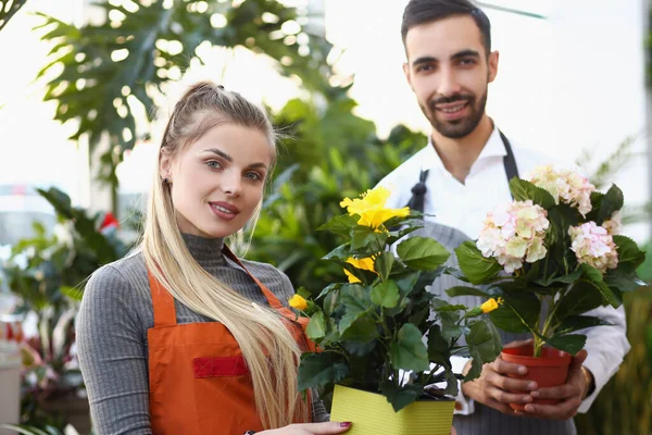 Cute florist workers hold flowers in pots, professional consultants ready to help with choice — Fotografia de Stock