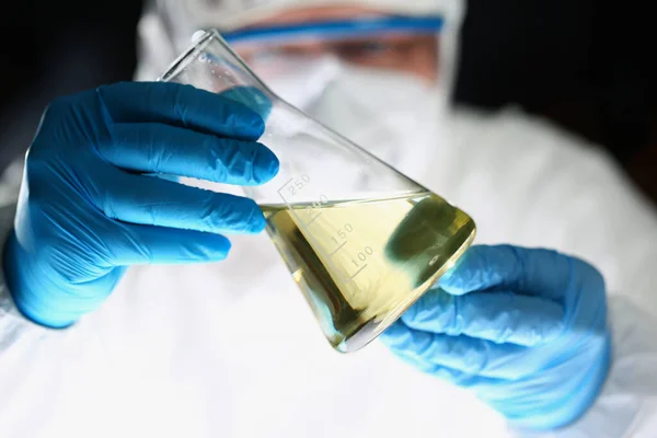 Pharmacien de laboratoire en respirateur et flacon étalon uniforme avec liquide jaune — Photo