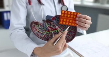 Doktor hapları tutuyor ve karaciğer taklidi yapıyor.