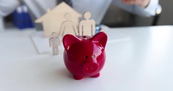Insurance agent protects t piggy bank and family with house with hands — Video Stock