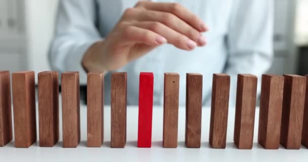 Female hand selects red block from row of beige wooden blocks — Stockvideo