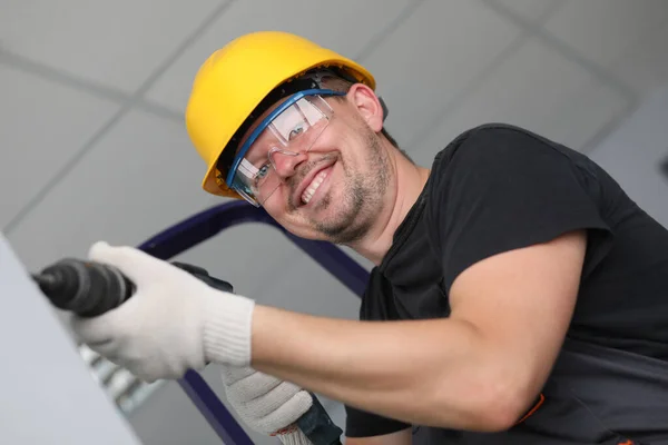 Construtor sorridente na parede de perfuração capacete em casa — Fotografia de Stock
