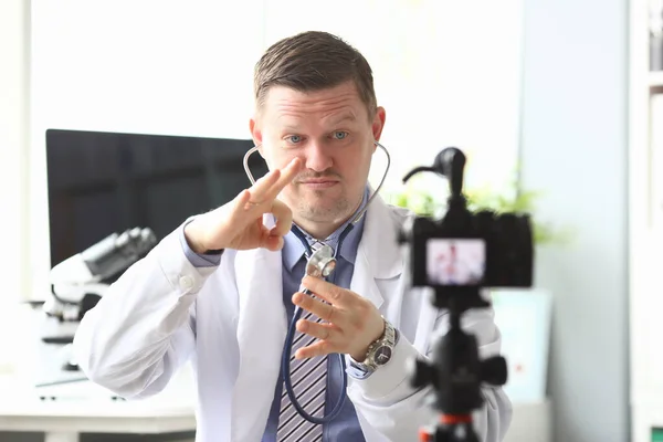Hombre médico golpeando en estetoscopio delante de la cámara en la clínica — Foto de Stock