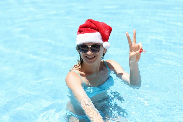 Молода усміхнена жінка в капелюсі Санта Клауса в басейні — стокове фото