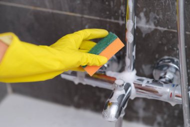 Eldivendeki bir el, mikseri süngerle yıkar.