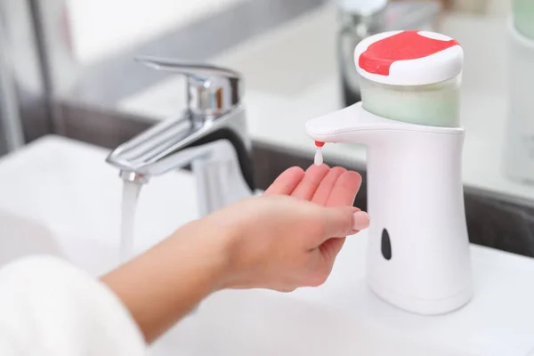 Een druppel zeep van een dispenser druipt op een vrouwenhand, — Stockfoto