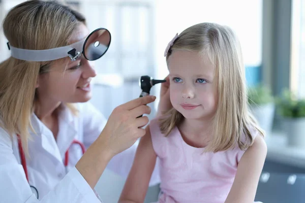 Klinikte bir kadın otolarolog bir kızın kulağına bakar. — Stok fotoğraf