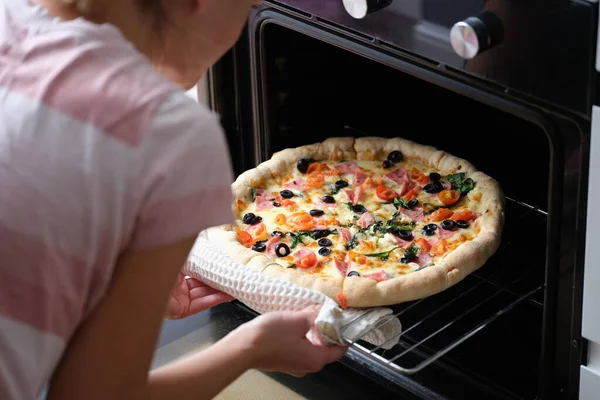 Bir kadın ev yapımı pizzayı fırından çıkarır. — Stok fotoğraf