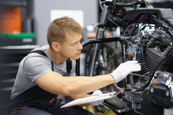 En man i garaget kollar en motorcykel. — Stockfoto