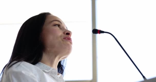 Presentadora femenina frente al micrófono habla a la audiencia durante la presentación — Vídeo de stock