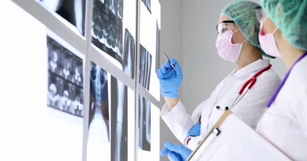 Médicos en máscaras protectoras y gafas mirando rayos X en la oficina de la clínica 4k película cámara lenta — Vídeo de stock