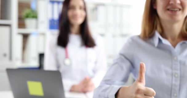 Woman showing thumb up against background of doctor in clinic closeup 4k movie slow motion — Vídeo de Stock