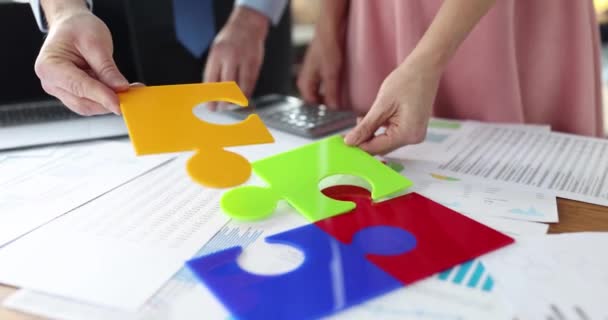 Business people putting together colorful puzzle at table in office closeup 4k movie slow motion — Stock video