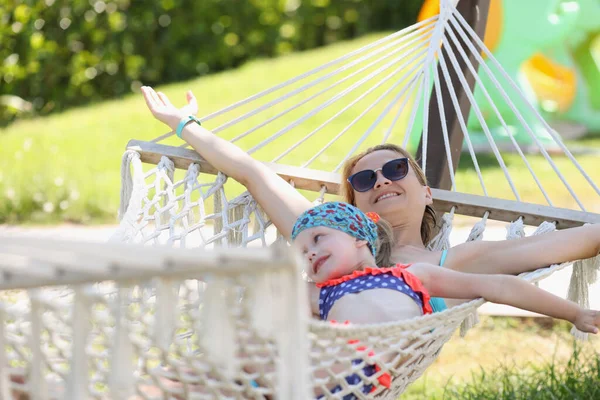 Happy mother with daughter lay on hammock in shadow, enjoy life and vacation — Stock fotografie