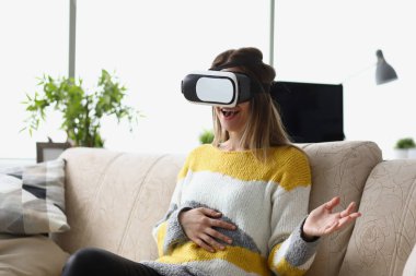 Female sit on sofa wear vr glasses modern device, enjoy spare time in imagination world