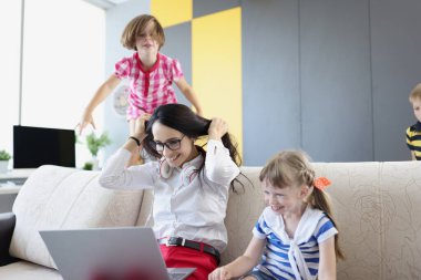 Happy woman working and playing with her kids on couch