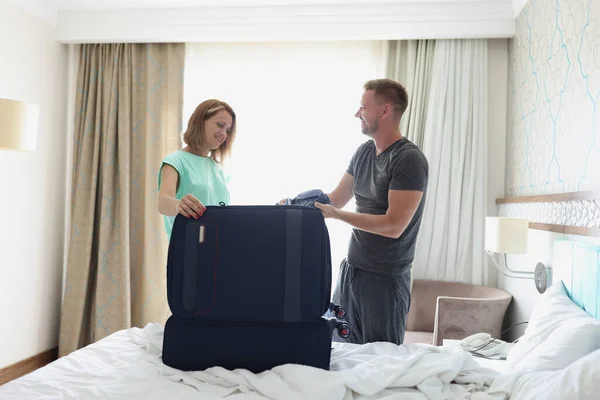 Жінка дружина допомагає чоловікові упакувати речі у валізу для поїздки на роботу — стокове фото