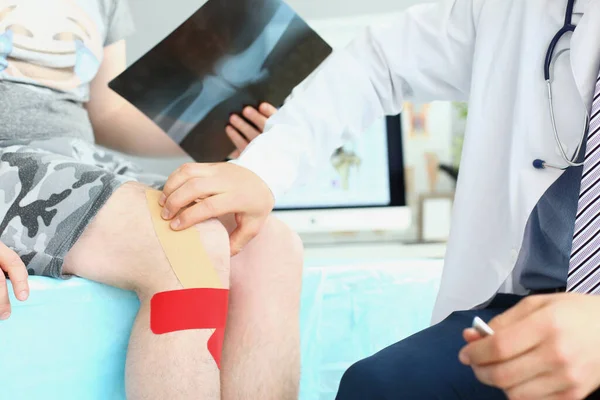 Physician wear uniform and stethoscope carefully examining patient leg — Stockfoto