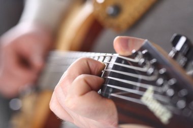 Male hands holding and playing wooden guitar