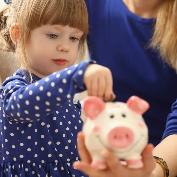 Little child girl with mom throws coins into piggy bank — Stockfoto