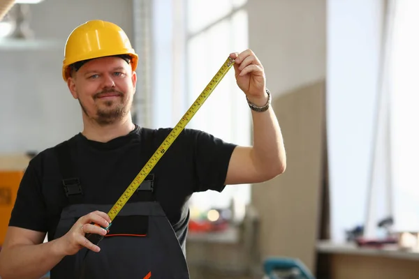 Worker in helmet and uniform holds tape measure — Zdjęcie stockowe
