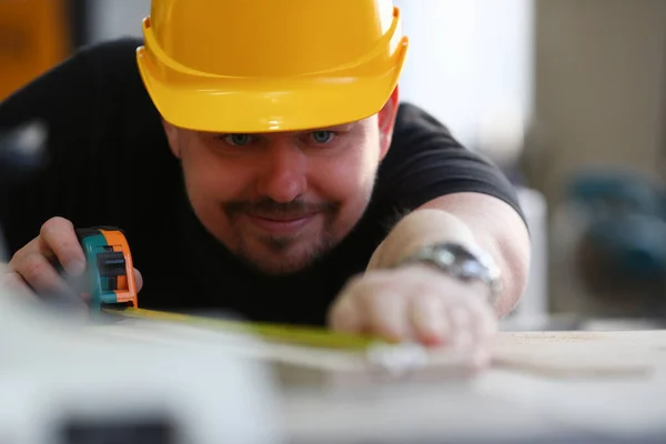 Man builder in helmet makes measurements with tape measure — Stock Fotó