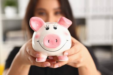 Young woman holding piggy bank in hands pink pig piggy bank