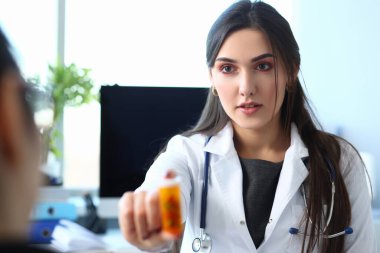 Female medicine doctor hand hold jar of pills in clinic