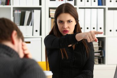 Aggressive female boss points hand to exit, dismissing sad employee