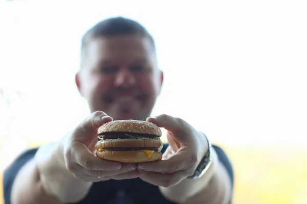 Young man holds hearty hamburger in hands — Fotografia de Stock