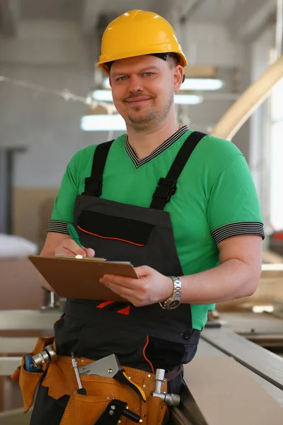 Worker in helmet and in uniform holds clipboard — Fotografia de Stock