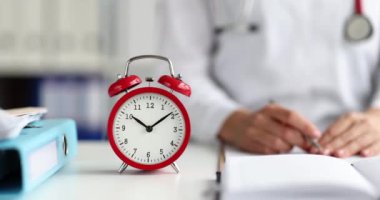 Red alarm clock stands at workplace of doctor